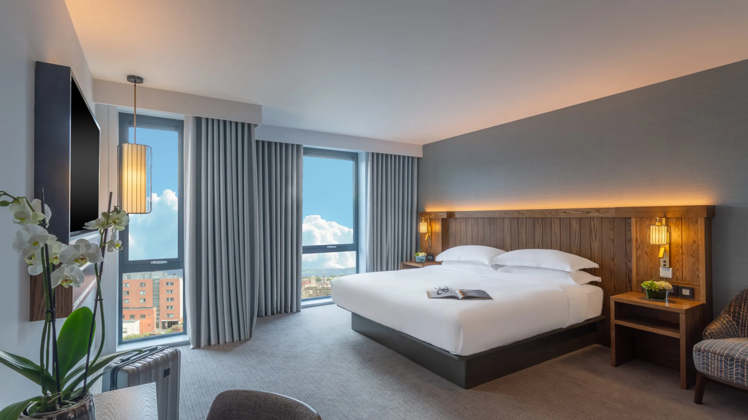 Hyatt Centric Dublin hotel guest room with desk, floor to ceiling windows and grey carpet.