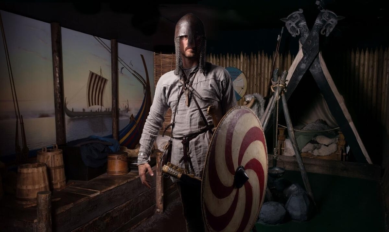 Medieval reenactor in armor with shield and sword on a Viking ship.