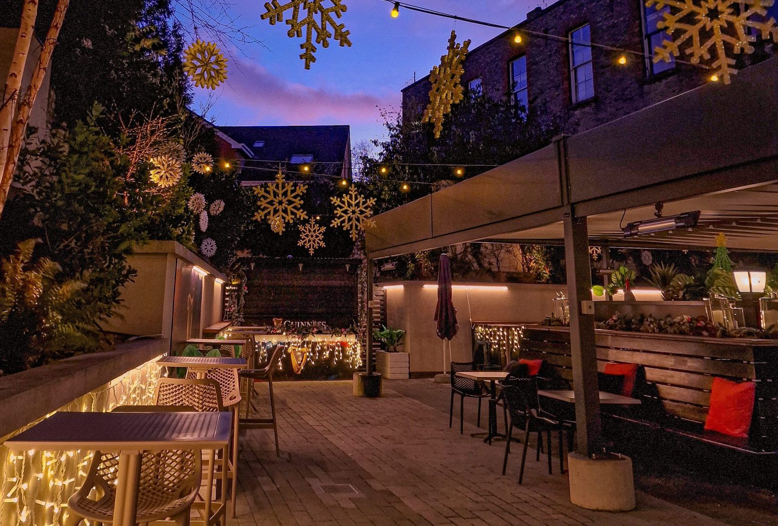 Outdoor patio with string lights and snowflake decorations at dusk.